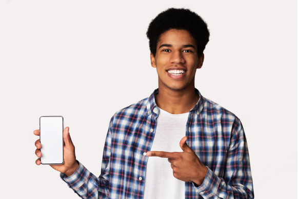 Imagen de un joven sonriente señalando su teléfono celular.