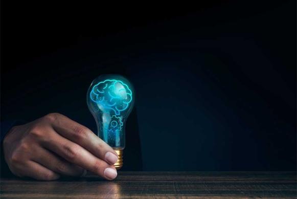 Imagen de una mano sosteniendo una bombilla con un cerebro que representa la innovación tecnológica.