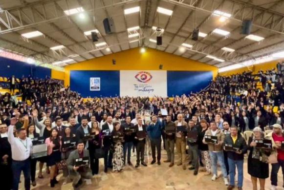 Fotografía del Ministro TIC, Mauricio Lizcano rodeado de ciudadanos en recinto cerrado.